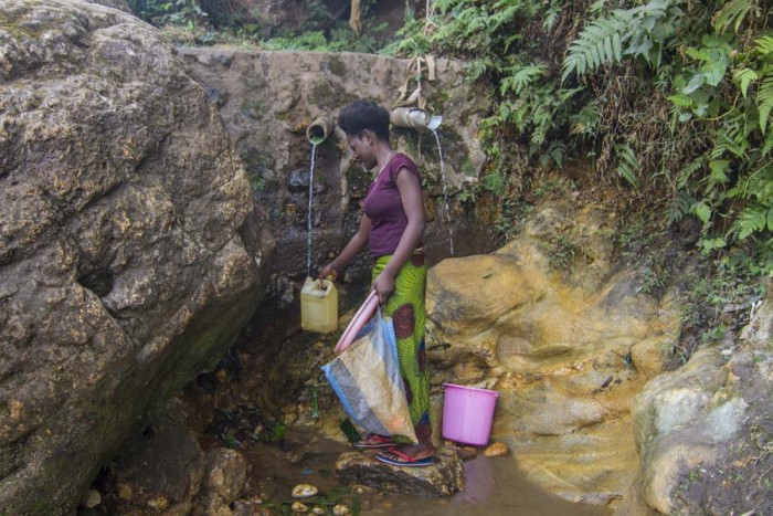 A woman is fetching water from the water site in Kwen.
