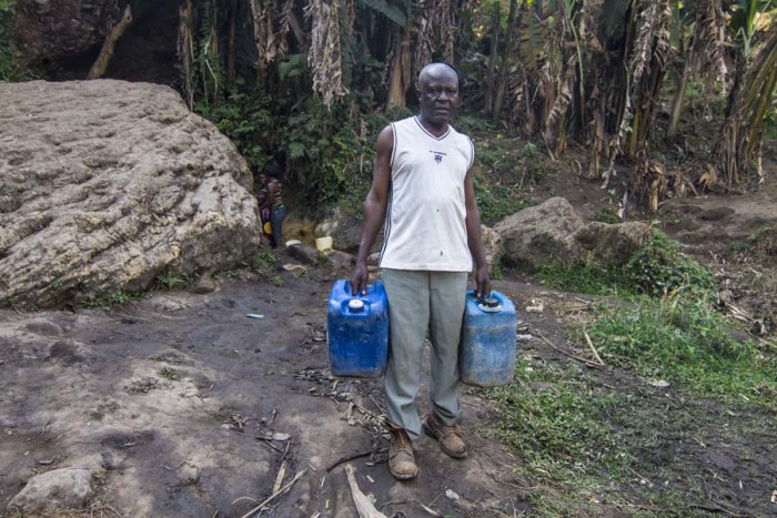 A man carries two jugs that carry about six gallons of water in Kwen.